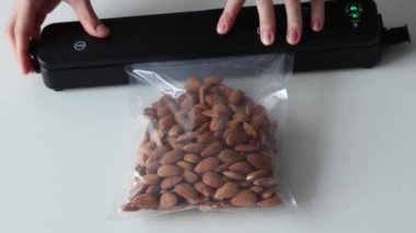 Uzun vadeli depolama için badem fıstığı paketleyen süpürge. Ürünleri uzun vadeli depolamak için vakumlu paketleyici kullanıyor. Ev mutfağındaki süpürge ambalaj makinesi.
