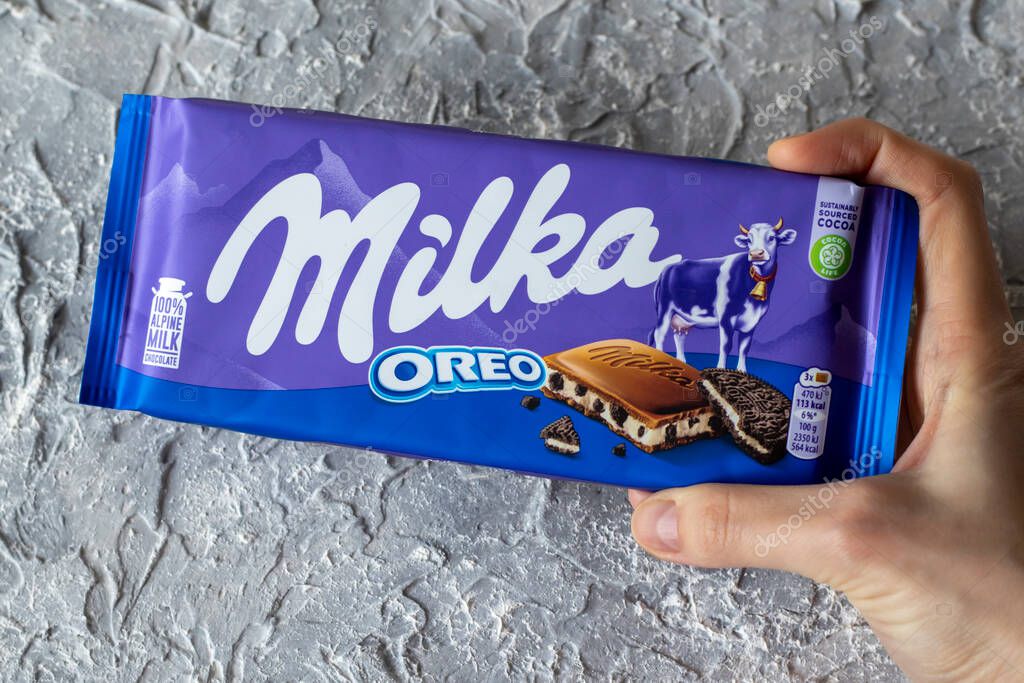 IRPEN, UKRAINE, DECEMBER 20 20222, Milka OREO alpine milk chocolate in the hand of a woman on a gray background, Illustrative Editorial