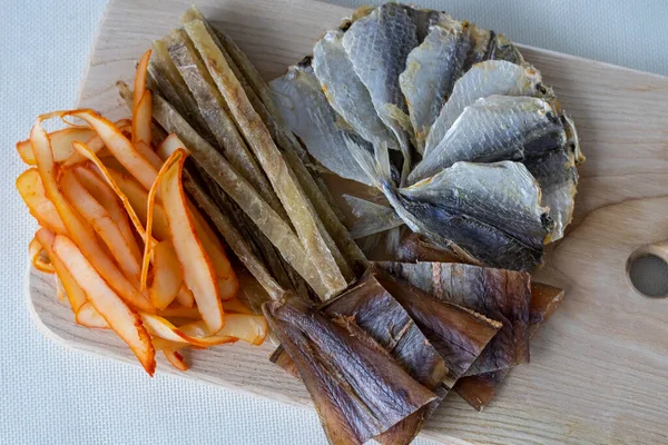 stock image Wooden board with lots of beer snacks. Dried salted mackerel fish, cod fillets, calamari and peppers, tuna and caviar. An appetizer for a campaign of people