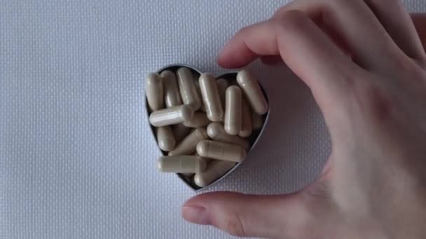 Бежевые Медицинские Капсулы Таблетки Добавки Сердце Белом Фоне Разбросанном Всей — стоковое видео
