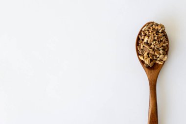 Burdock Root Herb Herbal Medicine. Dried Finely Chopped Root in a Wooden Spoon on a White Background with Copy Space