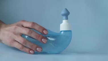Neti Pot. Ayurvedic medical tools for cleaning your nose with water and salt at home. Blue bowl of water in a womans hand.
