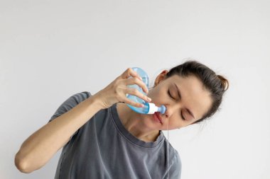 Girl rinses her nose with saline solution at home Using Neti Pot. Treatment and prevention of colds. How to rinse your nose when you have a runny nose