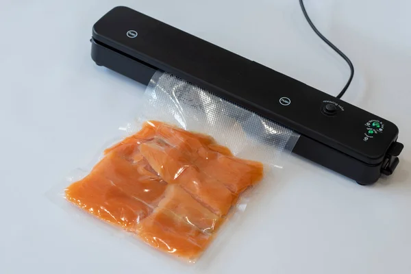 Vacuum packaging machine packs salmon fillets in a vacuum bag for pickling or sous-vide cooking.