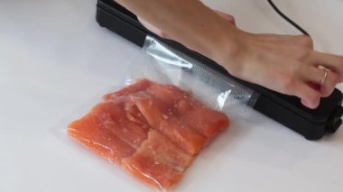 Vacuum packaging machine packs salmon fillets in a vacuum bag for pickling or sous-vide cooking. Vacuuming process.
