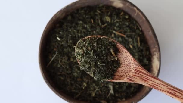 乾燥したイラクサは プレートとベージュの背景に木製のスプーンで薬用茶を作るための葉 — ストック動画