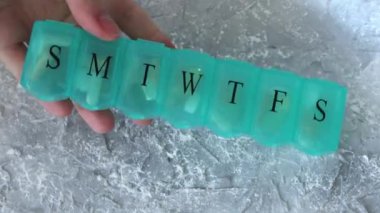 Filled pill organiser in a womans hand. Daily vitamin and supplement boxes for the week