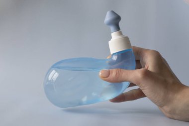 Neti Pot. Ayurvedic medical tools for cleaning your nose with water and salt at home. Blue bowl of water in a womans hand.