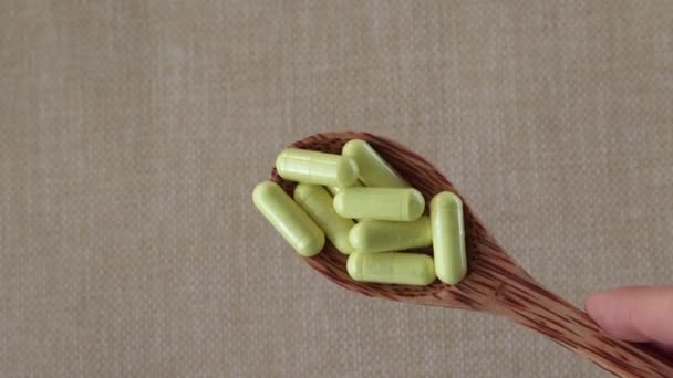 ベージュ地に木製のスプーンで黄色のケルセチンカプセル 栄養補助食品 ビタミンやタブレット 上からのクローズアップビュー アレルギー 喘息の治療 — ストック動画
