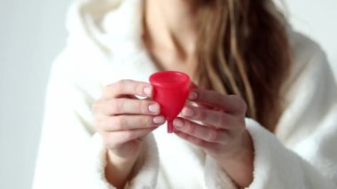 Young woman holds a menstrual cup in her hands. Feminine hygiene alternative product instead of tampon during period. Menstruation, critical days, women periods. Zero waste, eco, ecology