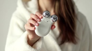 Microcurrent device. for massage of a womans face in her hands, selective focus, close-up