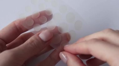 Sivilceler için yuvarlak yamalar ve beyaz arka plandaki ellerde kırışıklıklar. Sivilce ve yüz yenileme için kırışıklık bantları. Kozmetik bilimi temizliği. Kadınların elinde şeffaf bir çıkartma olur.
