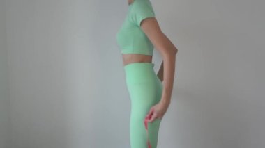 Girl measuring her butt and hips with a centimeter tape. Beautiful young fitness woman in sports leggings and top. Concept of weight loss, proper nutrition, fitness.