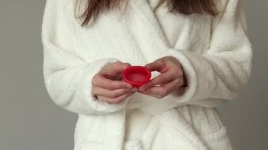 Young woman holds a menstrual cup in her hands. Feminine hygiene alternative product instead of tampon during period. Menstruation, critical days, women periods. Zero waste, eco, ecology