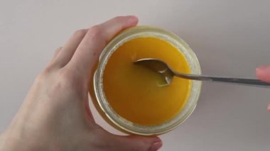 Cam kavanoz ve bir kaşık Ghee yağı beyaz arka planda, yakın plan.