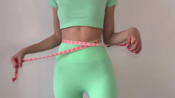 穿着绿松石短袜的年轻瘦弱女子用带子量她的腰围 饮食和减肥的概念 — 图库视频影像