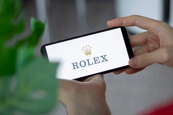 IRPEN, UKRAINE - JANUARY 20 20223, Closeup of smartphone screen with logo lettering of Rolex in mans hands, Illustrative Editorial