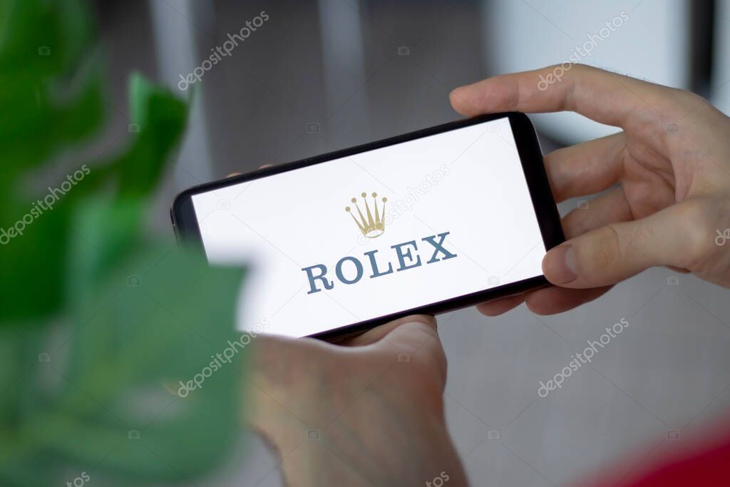 IRPEN, UKRAINE - JANUARY 20 20223, Closeup of smartphone screen with logo lettering of Rolex in mans hands, Illustrative Editorial