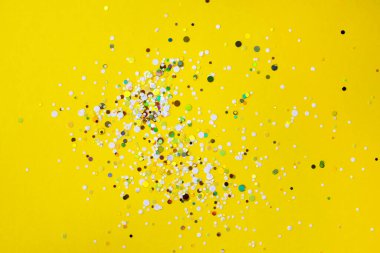 Flatlay of bright yellow background with colourful paper confetti with copyspace.
