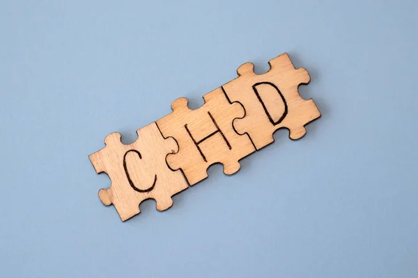 CHD word written on wooden puzzles on blue background. Healthcare conceptual for hospital, clinic and medical busines. CHD acronym coronary heart disease.