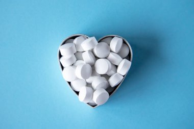 White round heart-shaped tablets on a blue background