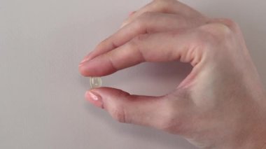 A vitamin d3 capsule in a womans hand in close-up. Fish oil pill or vitamin D supplement