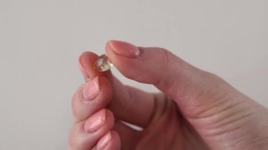 A vitamin d3 capsule in a womans hand in close-up. Fish oil pill or vitamin D supplement
