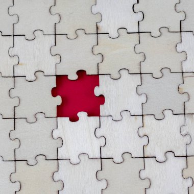 Absence wooden puzle on a red background. Missing Piece. The concept of lack and incompleteness. Square Photo.
