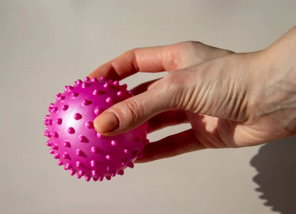 Woman is holding a pink spiked ball. Massage Ball Can Help You Release Knots and Soreness. Benefits of Using a Massage Ball for Myofascial Release.