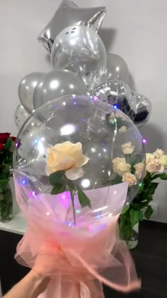 氦气球瀑布礼物 一朵玫瑰花插在气球里 手里拿着花环 垂直录像 — 图库视频影像