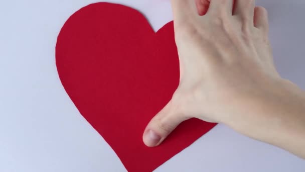 女性の手の半分に赤い紙の心を引き裂く — ストック動画