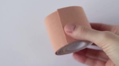 Roll of beige kinesio-tape on a white background, flat lay.