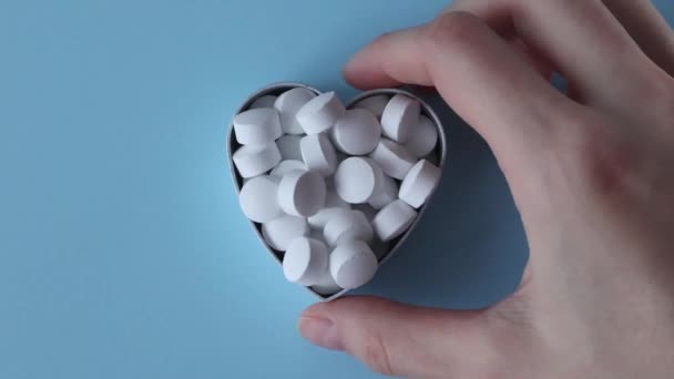Białe Okrągłe Tabletki Kształcie Serca Niebieskim Tle Tabletki Rozrzucone Powierzchni — Wideo stockowe