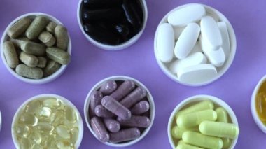 Cure diseases with pills and supplements. Purple background with lots of different sorted multicolored tablets