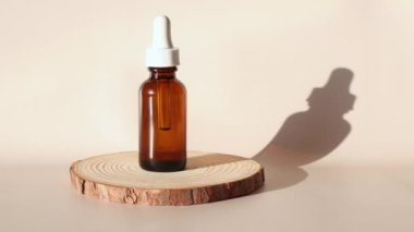 Serum or oil for the face and body moc up. A round wooden podium on a beige background, on which stands a dark glass bottle with a dropper