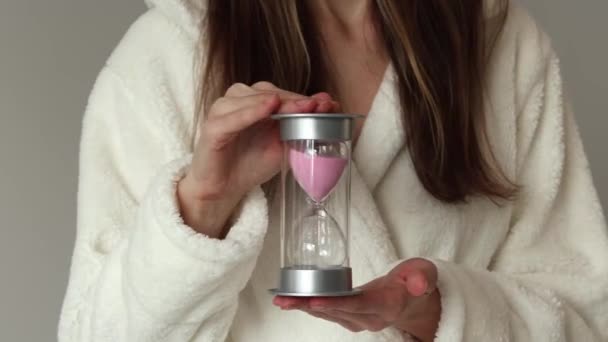Молодая Женщина Бежевом Халате Держит Затем Переворачивает Розовые Песочные Часы — стоковое видео