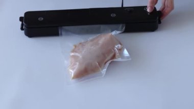 The process of packing chicken fillets in a vacuum bag using a special homemade machine that draws air and seals