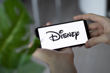 IRPEN, UKRAINE - JANUARY 20 20223, Closeup of smartphone screen Walt Disney Company logo lettering with in mans hands, Illustrative Editorial