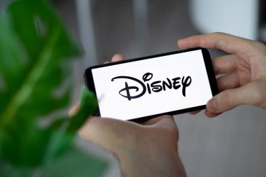IRPEN, UKRAINE - JANUARY 20 20223, Closeup of smartphone screen Walt Disney Company logo lettering with in mans hands, Illustrative Editorial clipart