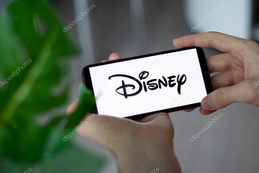 IRPEN, UKRAINE - JANUARY 20 20223, Closeup of smartphone screen Walt Disney Company logo lettering with in mans hands, Illustrative Editorial