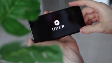 IRPEN, UKRAINE - JANUARY 20 20223, Closeup of smartphone screen uber logo lettering with in mans hands, Illustrative Editorial