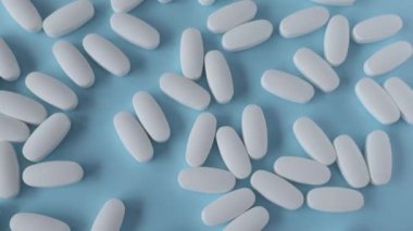L glutamine white oval tablets scattered on a blue background, view from above.
