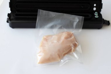 Vacuumed chicken breast near the vacuum machine on a white background. Preparing for cooking in sous vide.