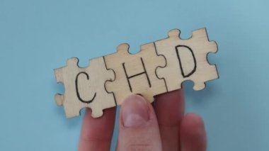 CHD word written on wooden puzzles on blue background. Healthcare conceptual for hospital, clinic and medical busines. CHD acronym coronary heart disease.