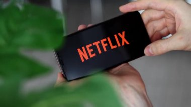 IRPEN, UKRAINE - JANUARY 20 20223, Closeup of smartphone screen logo Netflix on black background lettering with in mans hands, Illustrative Editorial