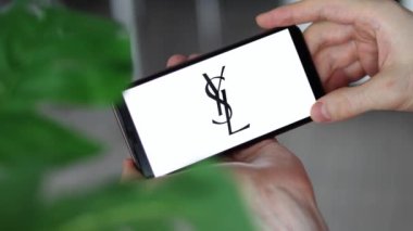 IRPEN, UKRAINE - JANUARY 20 20223, Closeup of smartphone screen logo lettering Yves Saint Laurent with in mans hands, Illustrative Editorial