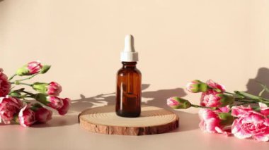 Kozmetik ürünlerin planı. Yüz ve vücut için kahverengi yağ şişesi ya da serum. Bej arka planda ahşap ve pembe çiçekler.