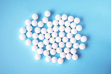 White round tablets, supplements on a blue background. Magnesium vitamins.