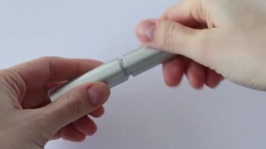 A woman opens a small gray tube with a thin brush of serum.