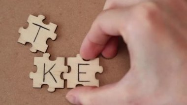 Woman assembles the word Keto out of wooden puzzles. The inscription is on a natural paper beige background. Lettering Keto.